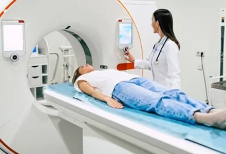 Patient undergoing CT scan with technician operating the machine.