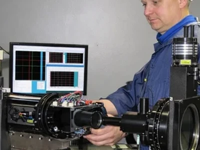 Engineer adjusting optical testing equipment in a laboratory.